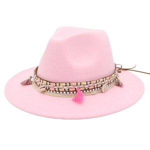 Detailed view of pink fedora hat with ethnic woven band, tassels and shell accents