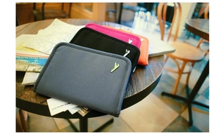 Nylon travel passport organizer bags in four colors on a cafe table with gold logo