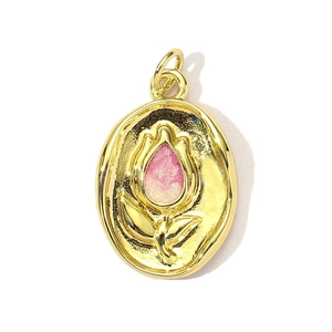 Macro view of gold-plated oval pendant featuring pink enamel floral tulip embossed detail