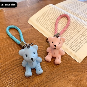 Close-up of blue and pink cartoon bear keychains on a rustic wooden desk with a book