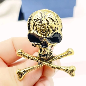 Punk style skull and crossbones brooch in gold finish with textured metal details