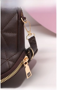 Close-up of golden metal hardware and zippers on a brown quilted leather crossbody bag
