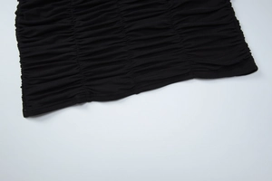 Close-up detail of the dense ruched texture and pleated knit fabric on black mini dress