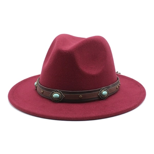 Détail d'un chapeau fedora bordeaux avec ruban en cuir marron et ornements turquoise