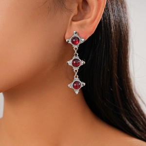 Close-up of vintage silver drop earrings with geometric deep red resin stones on a model