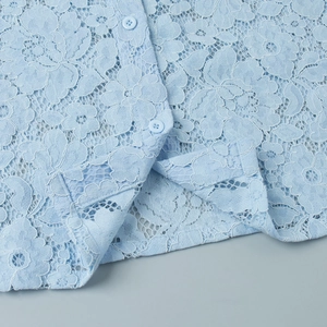 Detailed view of light blue lace shirt with intricate floral hollow patterns and buttons