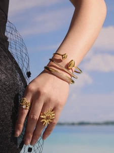 Détail de bracelets joncs et bagues plaqués or 18 carats avec zircons sur le poignet