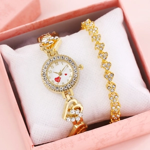 Close-up of gold women's watch and heart-shaped bracelet in a pink gift box
