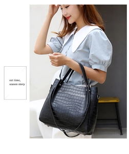 Detail of black crocodile texture tote bag showing its glossy finish and crossbody strap