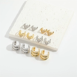 Dettaglio di ear cuff a strati in oro e argento con zirconi e motivi a cuore