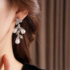 Détail de boucles d'oreilles élégantes avec fleurs et perles sur le mannequin