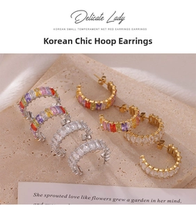 Détail macro de boucles d'oreilles en C avec zircons colorés sur fond de pierre