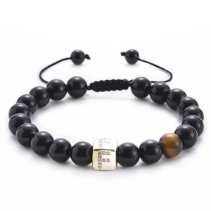 Detailed view of black onyx beads and tiger eye stone with golden micro-set zircon letter F