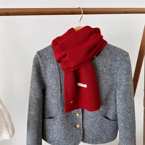 Thick red wool knit scarf for couples with a gray wool coat on a wooden hanger