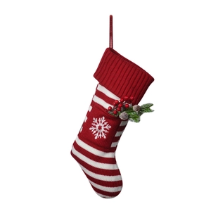 Detail of red and white striped knit Christmas stocking with snowflake embroidery and berries