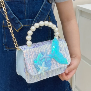 Girl's mermaid theme sequin handbag with pearl handle and marine charms on denim background