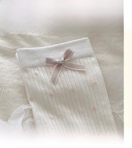 Dettaglio del polsino a coste elasticizzato e fiocco rosa su calze bianche stile balletto