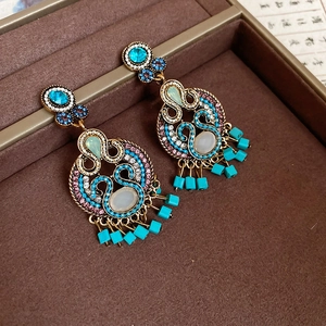 Detailed macro view of vintage bohemian gold earrings with emerald green gems and tassels