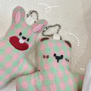 Detail of pink and green checkerboard plush bear and rabbit charms with embroidery