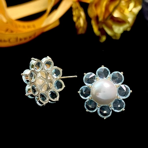 Elegant gold flower earrings featuring blue crystal petals and a central white pearl