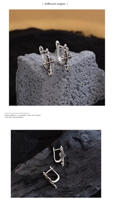 Detailed macro view of retro gothic cross earrings with vintage silver floral patterns