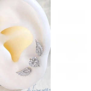 Detail of angel wing stud earrings set with sparkling cubic zirconia on a silicone ear model