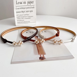 Elegant skinny pearl leather belts for women in brown, tan and white on a magazine