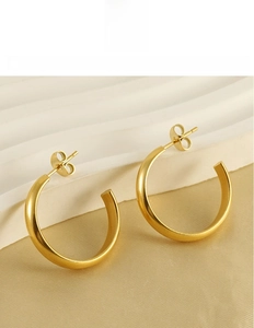 Detail of 18k gold plated titanium steel C-shaped hoop earrings on silk background