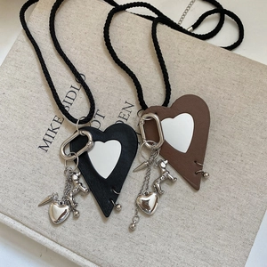 Close-up of leather heart and puppy charms on necklaces over a textured linen book