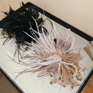 Detail of fabric butterfly hair claw with pearls, feathers and sequins on a mirror