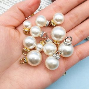 Handheld group of mixed size white faux pearl charms with rhinestone gold alloy loops