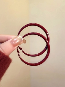 Macro shot of large minimalist deep red enamel hoop earrings with a glossy metal finish
