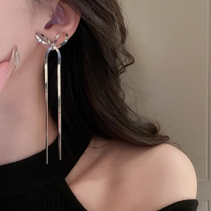 Detailed view of silver bow-shaped stud earrings with long metal snake chain tassels
