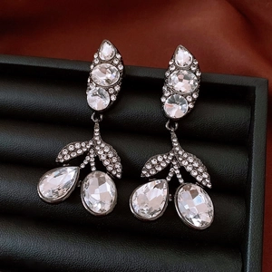 Macro de boucles d'oreilles vintage en forme de feuille avec cristaux sur support noir