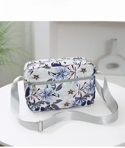 Detail view of double silver metal zippers and blue pink floral pattern crossbody bag