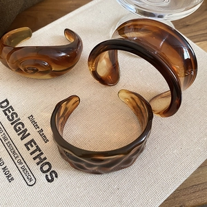 Detailed close-up of amber resin bangles with tortoiseshell texture and wave edges
