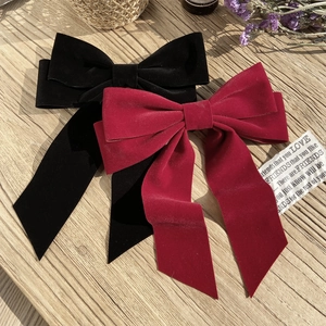 Elegant large velvet bow hair clips in black and wine red on a wooden background