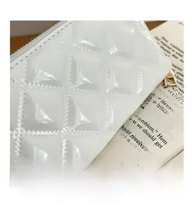 Detail of white glossy patent leather wallet featuring diamond quilted stitching pattern