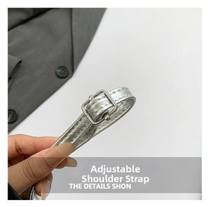 Detail of adjustable silver strap with crocodile texture and square metal buckle