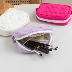 Close-up of heart-shaped quilted makeup bag with white zipper and inner mesh divider