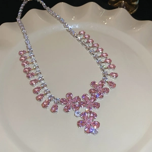 Dettaglio della collana a fiori rosa con zirconi cubici su un piatto di ceramica bianca
