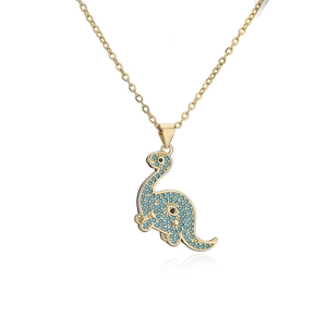Macro detail of gold-plated dinosaur pendant with shimmering blue zircon pavé setting