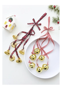 Close-up of golden Christmas bells with red plaid ribbons and festive pine branch decor