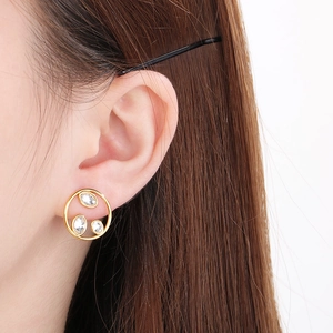 Close-up of gold hollow hoop earring with inlaid crystals worn by a model