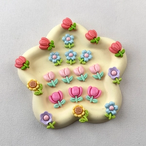 Close-up of colorful resin flower charms including tulips and sunflowers on a star tray