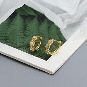 Detailed close-up of golden floral hoop earrings featuring sparkling zircon centers