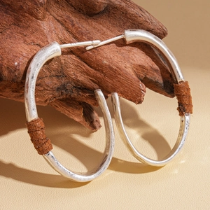 Silver geometric C-shape hoop earrings with hammered metal texture and brown leather wrap