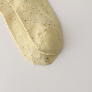 Close-up of yellow knit socks with colorful speckle pattern and toe seam detail