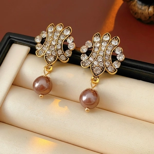 Macro detail of vintage gold earrings with fan-shaped rhinestones and brown pearls