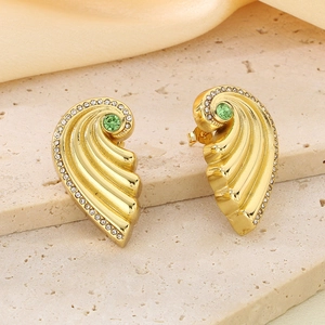 Detailed macro of golden wing earrings featuring green crystals and sparkling zircons